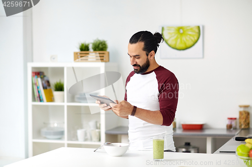 Image of man with tablet pc eating breakfast at home