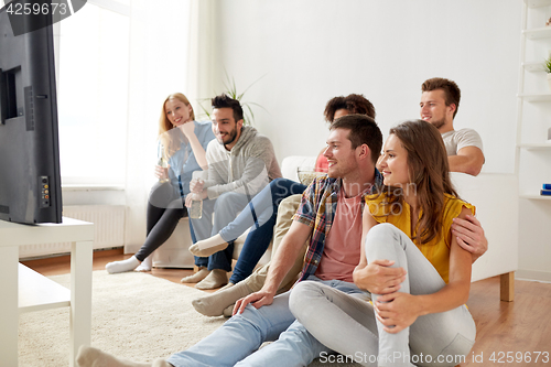 Image of happy friends with popcorn watching tv at home
