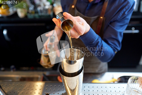 Image of bartender with shaker preparing cocktail at bar