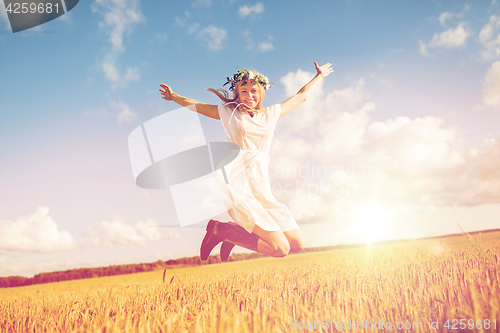 Image of happy woman in wreath jumping on cereal field