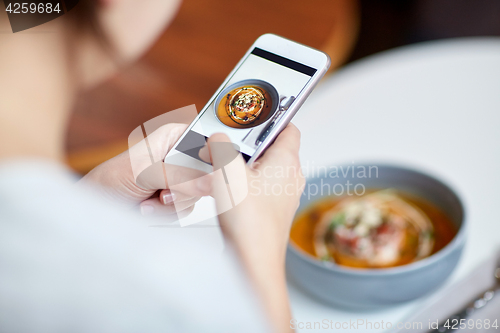 Image of woman with smartphone photographing food at cafe
