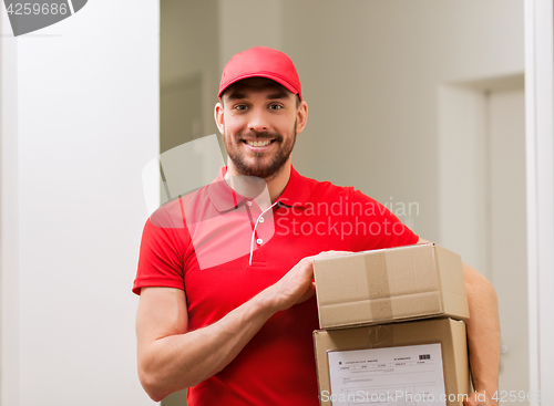 Image of delivery man with parcel boxes in corridor