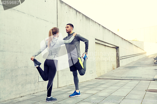 Image of couple of sportsmen stretching leg on city street