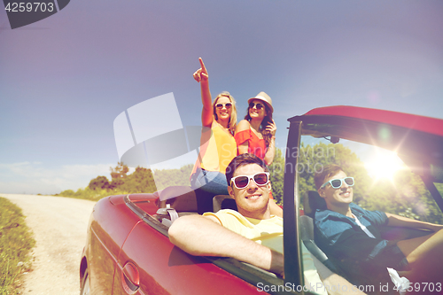 Image of happy friends driving in cabriolet car at country