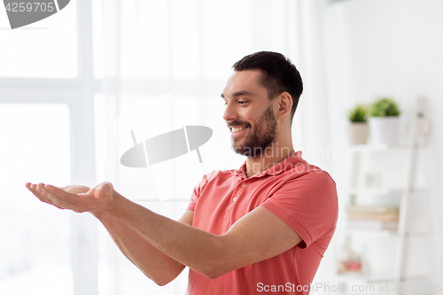 Image of happy man holding something imaginary at home