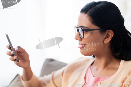 Image of happy woman texting message on smartphone at home