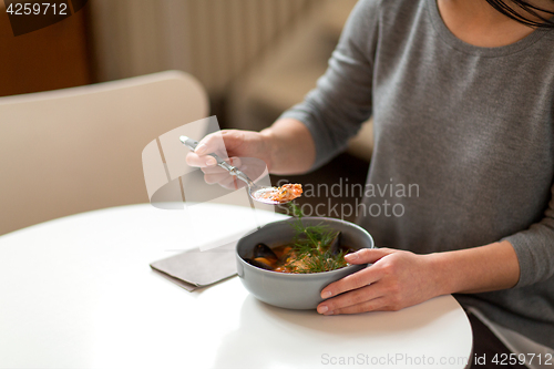 Image of woman eating fish soup at cafe or restaurant