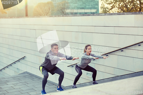 Image of couple doing squats on city street stairs