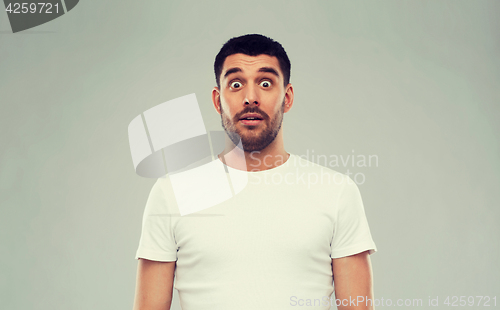 Image of scared man in white t-shirt over gray background