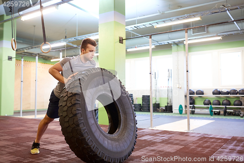 Image of man doing strongman tire flip training in gym