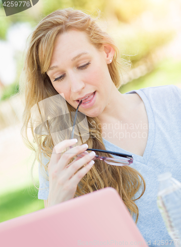 Image of Young Adult Woman With Glasses Outdoors Using Her Laptop.