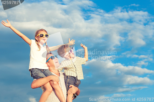 Image of Father and children playing in the park  at the day time.