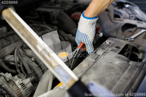 Image of mechanic man with pliers repairing car at workshop