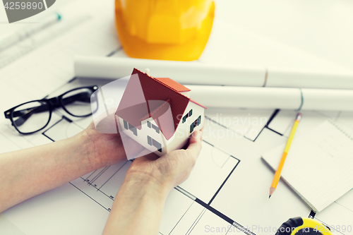 Image of close up of hands with house model above blueprint