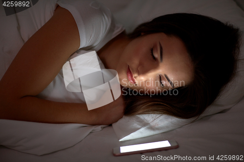 Image of woman with smartphone sleeping in bed at night