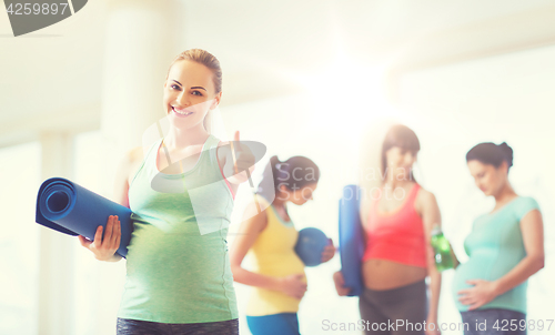 Image of pregnant woman with mat in gym showing thumbs up 