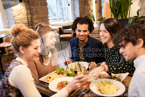 Image of friends with smartphone eating at restaurant