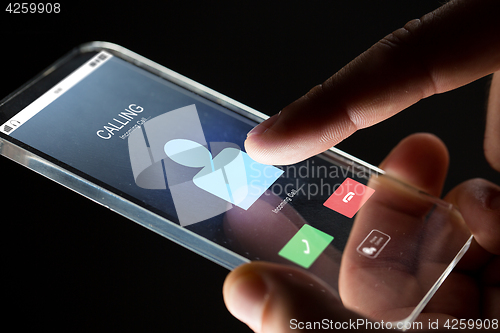 Image of close up of hand with incoming call on smartphone