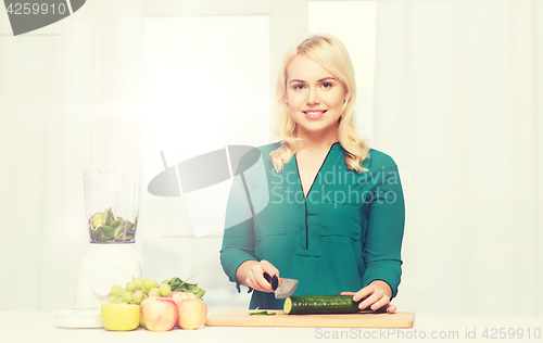 Image of smiling woman with blender cooking food at home