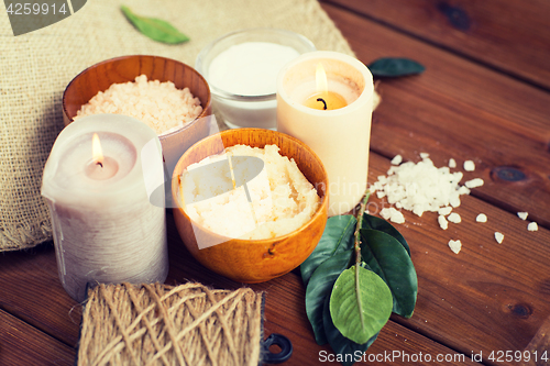 Image of close up of natural body scrub and candles on wood