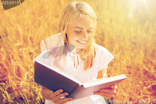 Image of smiling young woman reading book on cereal field