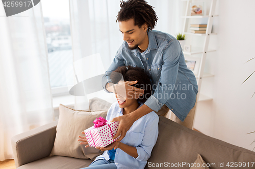 Image of happy couple with gift box at home