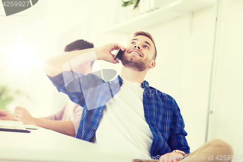 Image of happy creative man calling on cellphone at office