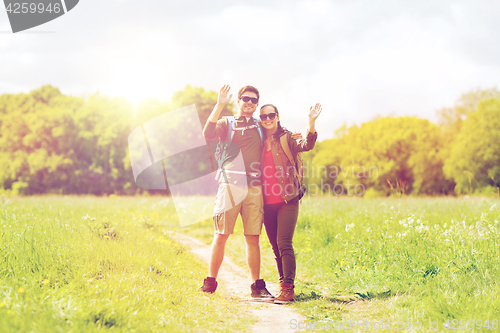 Image of happy couple with backpacks hiking outdoors