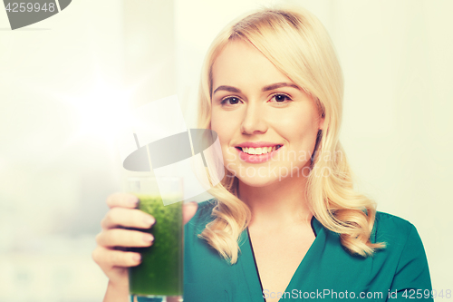 Image of smiling woman drinking juice or smoothie at home