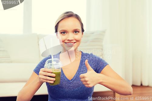 Image of happy woman with cup of smoothie showing thumbs up