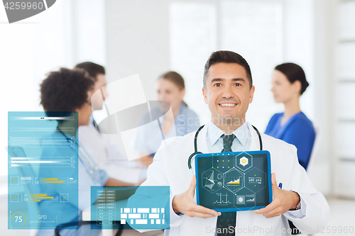 Image of happy doctor with tablet pc over team at clinic