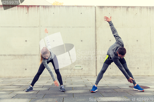 Image of close up of couple stretching on city street