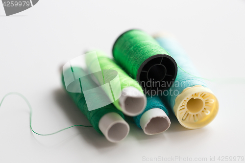 Image of green and blue thread spools on table