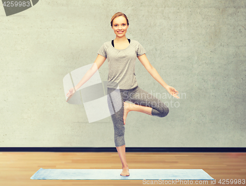 Image of woman making yoga in tree pose on mat