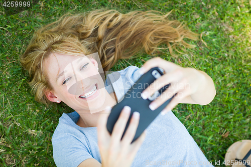 Image of Young Adult Woman Laying in Grass Taking a Selfie with Her Smart