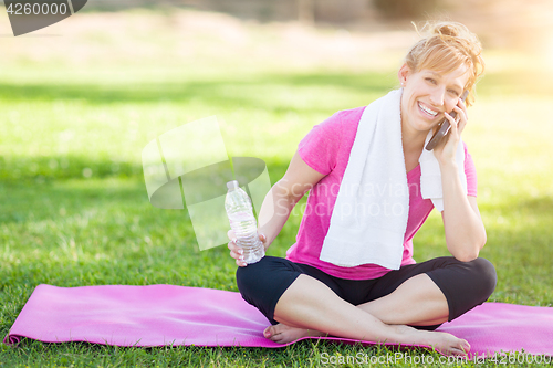 Image of Young Fit Adult Woman Outdoors with Towel and Water Bottle on Yo