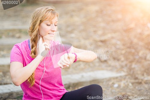 Image of Young Fit Adult Woman Outdoors in Workout Clothes Listening To M