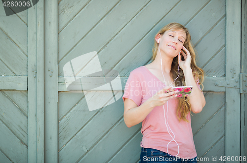 Image of Outdoor Portrait of Young Adult Brown Eyed Woman Listening To Mu