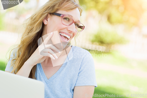 Image of Young Adult Woman Wearing Glasses Outdoors Using Her Laptop.