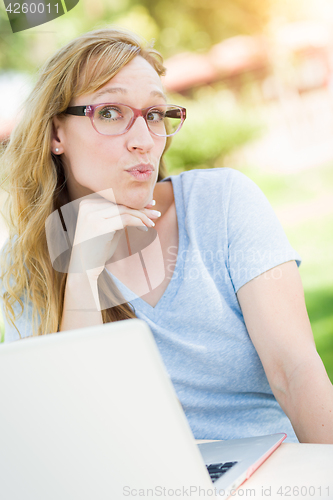 Image of Young Adult Woman Wearing Glasses Outdoors Using Her Laptop.