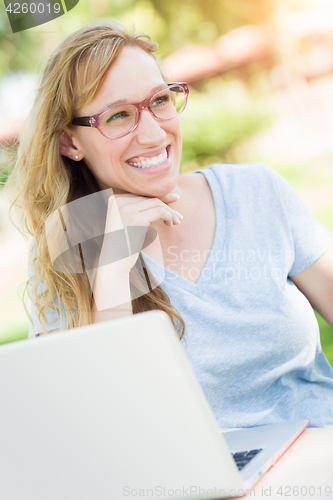 Image of Young Adult Woman Wearing Glasses Outdoors Using Her Laptop.
