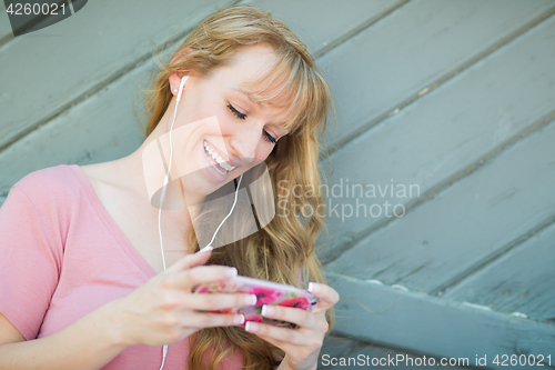Image of Outdoor Portrait of Young Adult Brown Eyed Woman Listening To Mu