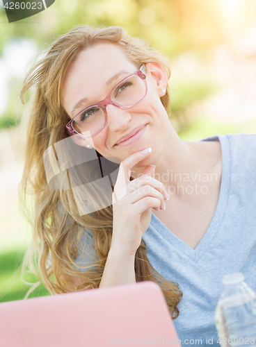 Image of Young Adult Woman Wearing Glasses Outdoors Using Her Laptop.