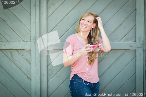 Image of Outdoor Portrait of Young Adult Brown Eyed Woman Listening To Mu