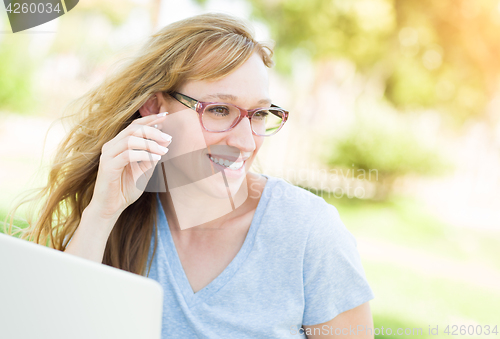Image of Young Adult Woman Wearing Glasses Outdoors Using Her Laptop.