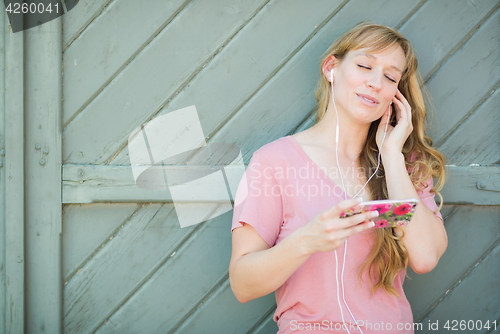 Image of Outdoor Portrait of Young Adult Brown Eyed Woman Listening To Mu