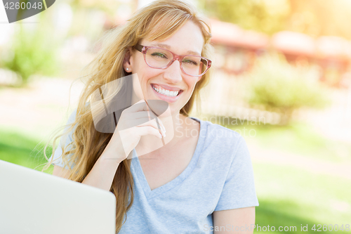 Image of Young Adult Woman Wearing Glasses Outdoors Using Her Laptop.