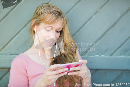 Image of Outdoor Portrait of Young Adult Brown Eyed Woman Listening To Mu