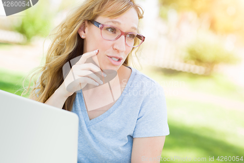 Image of Young Adult Woman Wearing Glasses Outdoors Using Her Laptop.