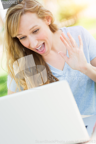 Image of Young Adult Woman Live Video Chatting Outdoors Using Her Laptop.
